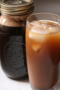 Iced coffee in a jar next to iced coffee in a glass